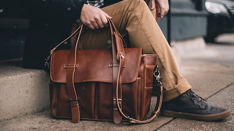 a man sitting on steps holding a brown leather bag