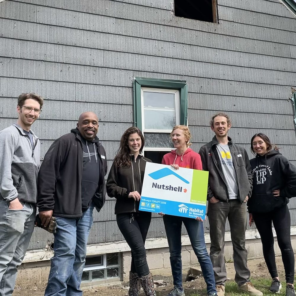 Nutshell employees standing in front of a house holding a Nutshell + habitats for humanity sign